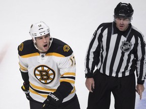 Boston Bruins' Milan Lucic reacts as he is escorted off the ice by linesman Michel Cormier after receiving a minor penalty in the final seconds of their game against the Montreal Canadiens  Thursday, October 16, 2014 in Montreal. (THE CANADIAN PRESS/Paul Chiasson)