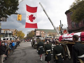 The body of Cpl. Nathan Cirillo is escorted through the streets toward his funeral service in Hamilton, Ont., on Tuesday, October 28, 2014. Cpl. Cirillo, 24, a reservist with the Argyll and Sutherland Highlanders of Canada, based in Hamilton was shot dead in Ottawa last Wednesday during an attack by an armed gunman at Parliament Hill. (THE CANADIAN PRESS/Peter Power)