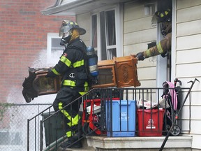 Windsor firefighters carry out a charred grandfather clock from a home at 2120 Secord Ave. in Windsor, ON.on Wed. Oct. 22, 2014. The home suffered extensive fire damage when a fire broke out at approximately 10:30 a.m. A woman and at least one child escaped the home before fire crews arrived. (DAN JANISSE/The Windsor Star)