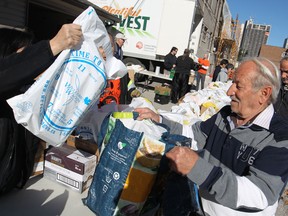 People pick up turkeys donated by Andy Jun, owner of Renu Kitchen Refacing, at the downtown Mission, Saturday, Oct. 11, 2014.  Potatoes, turnips, peppers, and desert were also given out to 250 people.  Another 250 turkeys were donated by Diane and Guy DaMarco and were given out at the Unemployed Help Centre.  (DAX MELMER/The Windsor Star)