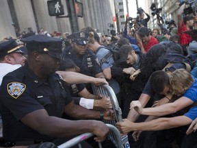 Pepper spray fired by police officers flies in the air as they attempt to secure a barricade blocking protestors from Wall Street during a march demanding action on climate change and corporate greed, Monday, Sept. 22, 2014, a day after a huge climate march in New York. (AP Photo/John Minchillo)