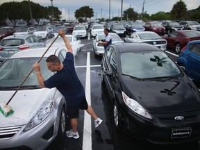 Employees wash new cars on the sales lot of a Ford AutoNation dealership in North Miami, Fla., in this September 2013 photo. (Joe Raedle / Getty Images files)
