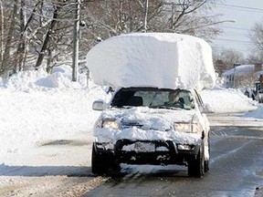 A vehicle, with a large chunk of snow on it's top, drives along Route 20 after digging out after a massive snow fall in Lancaster, N.Y. Wednesday, Nov. 19, 2014. Another two to three feet of snow is expected in the area.