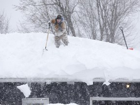 Tom Mudd clears snow from the roof of his house on Thursday, Nov. 20, 2014, in Cheektowaga, N.Y. A new blast of lake-effect snow pounded Buffalo for a third day piling more misery on a city already buried by an epic, deadly snowfall that could leave some areas with nearly 8 feet of snow on the ground when it's all done. (AP Photo/Mike Groll)