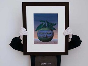 A Christie's employee holds a painting by Rene Magritte called 'Souvenir de voyage' at the auctions rooms in London, Thursday, Nov. 20, 2014. Two dozen modern and surrealist art works amassed by a private collector, including important paintings by Joan Miro and Rene Magritte, are set to fetch at least 64 million pounds ($100,435 ) when they go on auction in London next year.