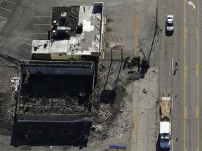 Workers dig in the parking lot of a building Tuesday, Nov. 25, 2014, in Ferguson, Mo., after it was burned in overnight protests following a grand jury's decision not to indict a white police officer in the killing of unarmed black 18-year-old Michael Brown. Monday night's protests were far more destructive than any of those that followed Brown's Aug. 9 death, with more than a dozen businesses badly damaged or destroyed. (AP Photo/Charlie Riedel)