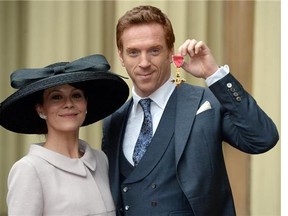 British actor Damian Lewis (R) poses with his wife Helen McCrory (L) as he holds his Officer of the Order of the British Empire (OBE) medal after an investiture ceremony at Buckingham Palace in London on November 26, 2014. Lewis recieved the honour for services to drama.
Photograph by: ANTHONY DEVLIN , Montreal Gazette
