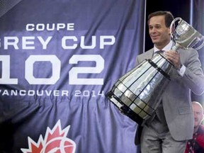 CFL commissioner Mark Cohon carries the Grey Cup during the 102nd Grey Cup in Vancouver, B.C. Sunday, Nov. 30, 2014. THE CANADIAN PRESS/Paul Chiasson