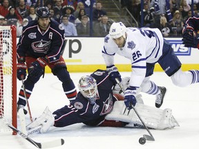 Toronto's Daniel Winnik, centre, dives over Columbus Blue Jackets goalie Curtis McElhinney, left, as Fedor Tyutin, left, and Jack Johnson close in Friday in Columbus. (AP Photo/Mike Munden)