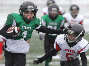 Titans' Nathan Smith, left, powers his way past the Giants' Anthony Elam during the tyke division final at Alumni Field Saturday. (DAN JANISSE/The Windsor Star)