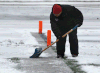 A coach clears snow from the field prior to a game at the Day of Champions at Alumni Field. (DAN JANISSE/The Windsor Star)