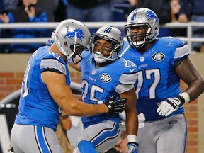 Theo Riddick, centre, of the Detroit Lions celebrates after scoring the game-winning touchdown with teammates Kellen Davis, left, and Cornelius Lucas at Ford Field on Nov. 9 , 2014 in Detroit, Michigan. The Lions defeated the Dolphins 20-16. (Photo by Leon Halip/Getty Images)