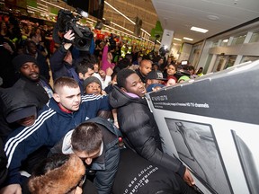 Shoppers jostle for electrical goods at a store in London, Friday Nov. 28, 2014. Americans celebrating Thanksgiving in Britain may have felt right at home as Black Friday shopping chaos caused some disruption. The practice of offering bargain basement prices the day after Thanksgiving has spread across the Atlantic, with some retailers opening overnight to lure determined shoppers. (AP Photo/PA, David Parry)