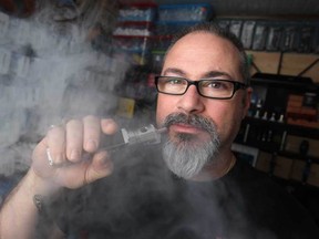 In this file photo, Paul Dinunzio, owner of Vapourama E-Cigarettes in Amherstburg, vapes from a Dovpo DT-50, a box mod using for vaping, at his store, Monday, Nov. 24, 2014.  (DAX MELMER/The Windsor Star)