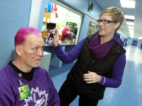 Karry Normandeau from Hiatus House paints Ken Mercer's hair purple during Purple Day at Forest Glade Arena in Windsor on Monday, November 23, 2014. Windsor Minor Hockey teams taped their sticks with purple tape all in support of Woman Abuse Awareness & Prevention Month.                    (TYLER BROWNBRIDGE/The Windsor Star)