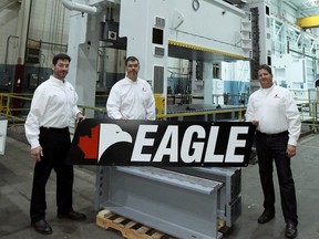 Brothers and owners Ed, left, Mark and Ted Polewski are seen with one of the massive presses their company, Eagle Press, builds in Tecumseh. (TYLER BROWNBRIDGE / The Windsor Star)