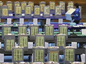 Election staff members carries a ballot box for vote counting in the parliamentary lower house elections at a ballot counting center in Tokyo, Sunday, Dec. 14, 2014.
