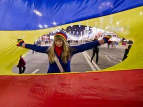 A girl poses for a picture inside a large symbolic revolution Romania flag with the communist crest cut out during a reenactment of the 1989 uprising in Bucharest, Romania, Sunday, Dec. 21, 2014.
