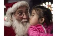A girl kisses a Santa Claus at the Intercontinental hotel of Beijing, on December,19, 2014. (Fred Dufour/Getty Images)