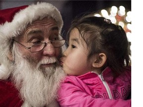 A girl kisses a Santa Claus at the Intercontinental hotel of Beijing, on December,19, 2014. (Fred Dufour/Getty Images)