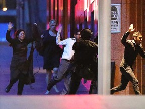 People run with there hands up from the Lindt Cafe, Martin Place during a hostage standoff on December 16, 2014 in Sydney, Australia.  Police stormed the Sydney cafe as a gunman has been holding hostages.  (Joosep Martinson/Getty Images)
