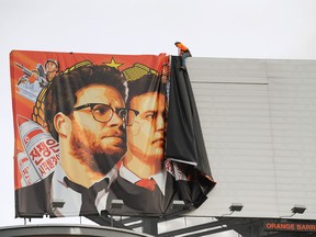Workers remove a poster-banner for "The Interview" from a billboard in Hollywood, California, December 18, 2014 a day after Sony announced was cancelling the movie's Christmas release due to a terrorist threat.  Sony defended itself Thursday against a flood of criticism for canceling the movie which angered North Korea and triggered a massive cyber-attack, as the crisis took a wider diplomatic turn.   AFP PHOTO / MICHAEL THURSTON