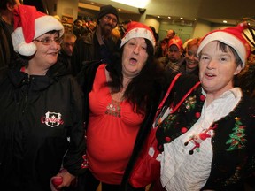 Happy carollers Loriann Wallace, left, Marlene Meloche and Melinda Rotta sing holiday songs while waiting for the annual Salvation Army Community Christmas Dinner at St. Clair College for the Arts  Wednesday December 17, 2014. About 1,000 dinners were prepare and served by Sally Ann staff and volunteers. (NICK BRANCACCIO/The Windsor Star)