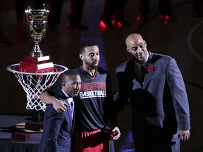 Windsor Express team president Dartis Willis, from left, R. J. Wells and head coach Bill Jones pose for photographs after Wells received his championship ring during pre-game ceremonies at the WFCU Centre.