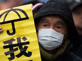 A protestor holds a banner with an umbrella during a protest march to the pro-democracy movement's main protest site in the Admiralty district of Hong Kong on Dec. 5, 2014. Benny Tai, a founder of Hong Kong's pro-democracy Occupy movement branded the occupation of the city's main roads as "high-risk", urging protesters to turn to new methods of civil disobedience to push for electoral reform.  AFP PHOTO / JOHANNES EISELEJOHANNES EISELE/AFP/Getty Images