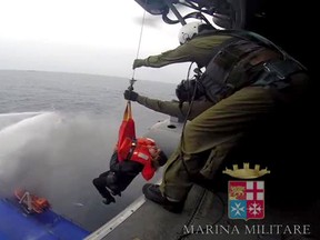 A photo grab taken from a video made available by the Marina Militare Italiana on December 28, 2014, shows the ongoing evacuation of passengers from the burning ferry "Norman Atlantic" (L) adrift off Albania. Desperate passengers pleaded by mobile phone live on TV to be saved from a burning ferry adrift off Albania as rescuers battled gale-force winds and billowing smoke to get to them. AFP PHOTO / HO/ MARINA MILITARE