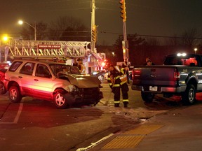 WINDSOR, ONT.: (12/13/14) -- A Windsor firefighter sweeps up after a three vehicle collision at the intersection of Lauzon Parkway and Forest Glade Drive Saturday evening, December 13, 2014. Two people were sent to hospital with non-life threatening injuries and a charge of careless driving was laid. (RICK DAWES/The Windsor Star)