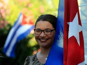 A woman holds a Cuban flag while celebrating the restoration of diplomatic relations between the island nation and the United States, in the courtyard of the Cuban Embassy in Santiago, Chile, Wednesday Dec. 17, 2014. (Luis Hidalgo/The Associated Press)