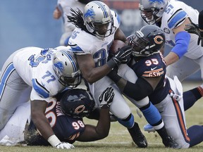 Detroit Lions running back Joique Bell (35) is tackled by Chicago Bears defensive tackles Brandon Dunn (98) and Ego Ferguson (95) during the first half Sunday, Dec. 21, 2014, in Chicago. (AP Photo/Nam Y. Huh)