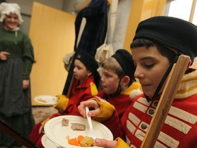 Max Lombardi, 12,  right, Tate Hargot, 10, and Anthony Tomac, 9 taste what a Christmas dinner for soldiers from 1812 might look like, consisting of a roast with stewed vegetables, during Fort Malden's Garrison Christmas event, Saturday, Dec. 20, 2014.  (DAX MELMER/The Windsor Star)
