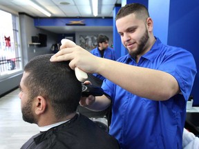 Mohamad El-Masri, owner of Scizzors Inc. hair salon in Windsor, ON. gives Robert Bonanni a cut on Tuesday, Dec. 16, 2014. His shop was vandalized on separate occasions causing significant damage and leaving racist remarks spray painted on the building. After months of renovating, they've finally reopened.  (DAN JANISSE/The Windsor Star)