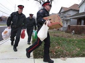The Windsor Police Service and Windsor Home Coalition Inc. hosted a "stuff-a-cruiser" event recently collecting food for needy families. The food collected will feed 120 families in the Windsor area. Sgt. Andrew Moxley, left, Sgt. Matt D'Asti and Const. Andrew Drouillard deliver some of the food on Wed. Dec. 17, 2014. (DAN JANISSE/The Windsor Star)