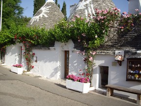 Traditional Apulian houses known as "trulli" line a street in Alberobello in the Puglia region of Italy. Trulli houses have a distinct conical roof structure.  A trullo (plural, trulli) is a traditional Apulian dry stone hut with a conical roof. Their style of construction is specific to the Itria Valley. (Photo by Loraine Whysall)