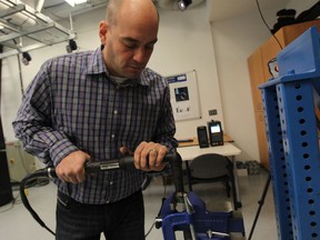 Joel Cort, an assistant professor of kinesiology at University of Windsor, is leading a research project into designing automotive assembly tools that help reduce the risk of workplace injuries.  Cort is shown testing an assembly tool. (JASON KRYK / The Windsor Star)