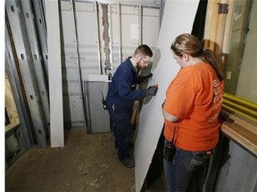 General Motors millwrights Mike Edwards, rear, and Chris Mathis work on drywall panels inside a container home being remodeled inside the GM Detroit-Hamtramck Assembly plant in Detroit. (AP Photo/Carlos Osorio)