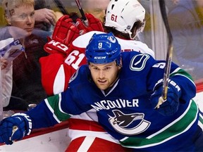Zack Kassian crunches Detroit Red Wings defenceman Xavier Ouellet into the boards at Rogers Arena on Saturday, when the Vancouver Canucks winger played his first game since breaking a finger Nov. 25.
Photograph by: Gerry Kahrmann , PNG