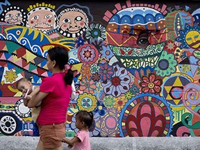 A mother holding a baby walks past graffiti painted on a wall in Manila on January 26, 2015.  AFP PHOTO / NOEL CELISNOEL CELIS/AFP/Getty Images