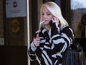 Sabrina Lacommare holds a phone to her ear while lighting up as she leaves Superior Court in Windsor, Tuesday January 27, 2015. (NICK BRANCACCIO/The Windsor Star)