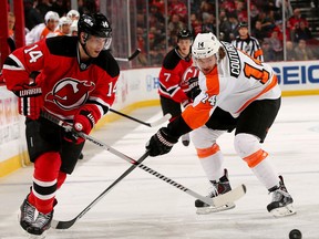 New Jersey's Adam Henrique, left, passes the puck as Philadelphia's Sean Couturier defends at Prudential Center on January 7, 2014  in Newark, New Jersey.  (Photo by Elsa/Getty Images)