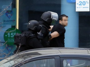 A man (R), who had taken two hostages in a post office, is arrested by French Research and Intervention Brigades (BRI) police officers on January 16, 2015 in Colombes, outside Paris. Police sources said several post office clients had managed to escape and that the gunman himself had called them. The sources said he was "speaking incoherently" and was heavily armed with grenades and Kalashnikovs. The French capital is still jittery after a series of attacks last week by Islamist gunmen left 17 people dead. AFP PHOTO / THOMAS SAMSONTHOMAS SAMSON/AFP/Getty Images