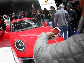 A man takes a picture of a Porsche during the North American International Auto Show at Cobo Hall on Saturday, Jan. 17, 2015 in Detroit, Mich. (DAX MELMER/The Windsor Star)