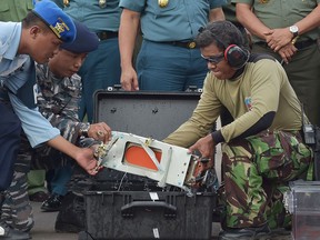 Indonesian military personnel remove Flight Data Recorder of the ill-fated AirAsia flight QZ8501 into a proper case in Pangkalan Bun, Indonesia, Monday, Jan. 12, 2015. Divers retrieved one black box Monday and located the other from the AirAsia plane that crashed more than two weeks ago, a key development that should help investigators unravel what caused the aircraft to plummet into the Java Sea.  (AP Photo/Adek Berry, Pool)