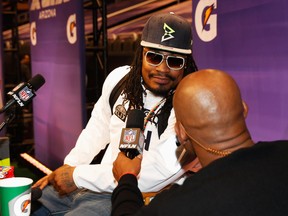 Marshawn Lynch #24 of the Seattle Seahawks talks with NFL Network personality Deion Sanders at Super Bowl XLIX Media Day Fueled by Gatorade inside U.S. Airways Center on January 27, 2015 in Phoenix, Arizona.  (Photo by Christian Petersen/Getty Images)
