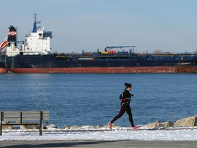 A ship sits anchored in the middle of the Detroit River as a woman runs past on a chilly day in Windsor on Monday, January 26, 2015.       (TYLER BROWNBRIDGE/The Windsor Star)