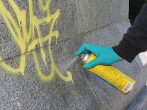 A public works employee in Victoria, B.C., applies paint remover to graffiti on a memorial in this 2008 file photo. (Bruce Stotesbury / Victoria-Times Colonist)