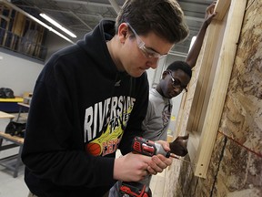 St. Joseph's students James Kennedy, left, and Dami Alalade install a window in a construction technology class at St. Joseph's in Windsor on Wednesday, January 28, 2015.     (TYLER BROWNBRIDGE/The Windsor Star)